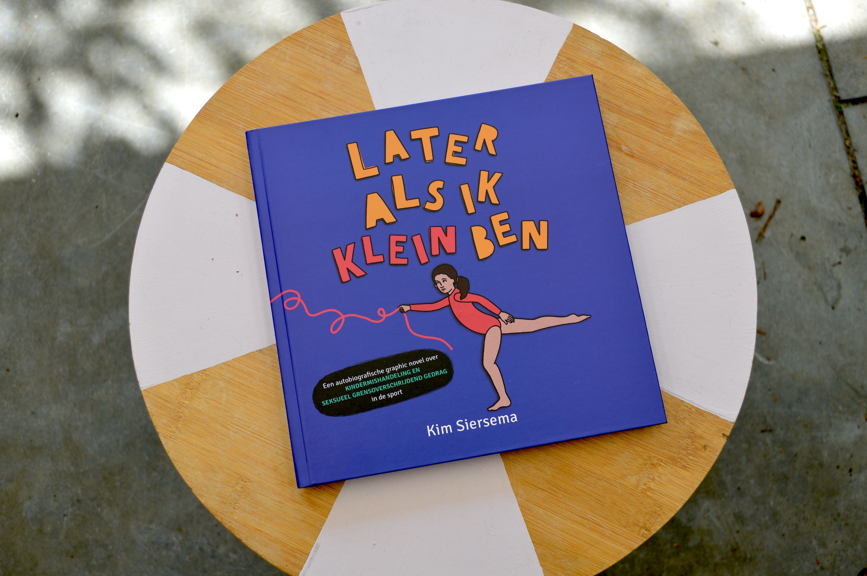 hier zie je een exemplaar van het boek later als ik klein ben. De cover is paars met de titel erop. En een turnmeisje wat een roze touw vasthoudt.